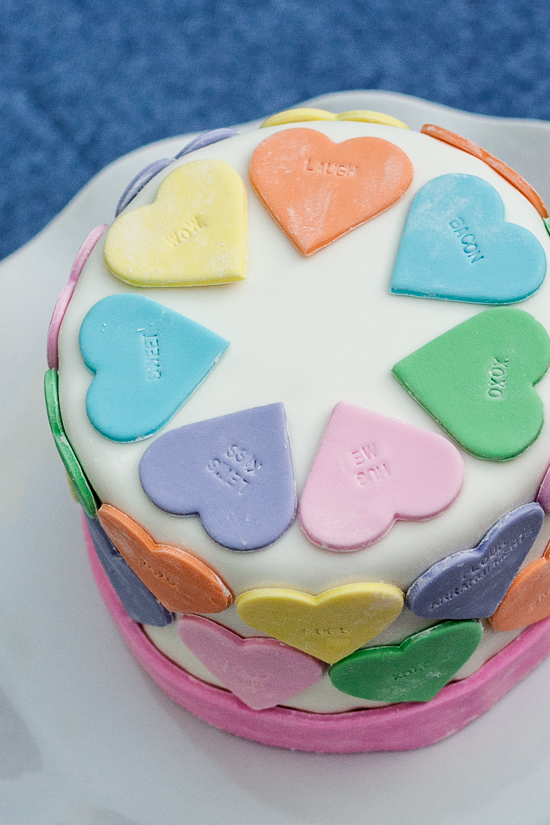Pastel fondant hearts and a customizable letter stamp help create a personalized conversation hearts cake. It's the perfect cake for Valentine's Day!
