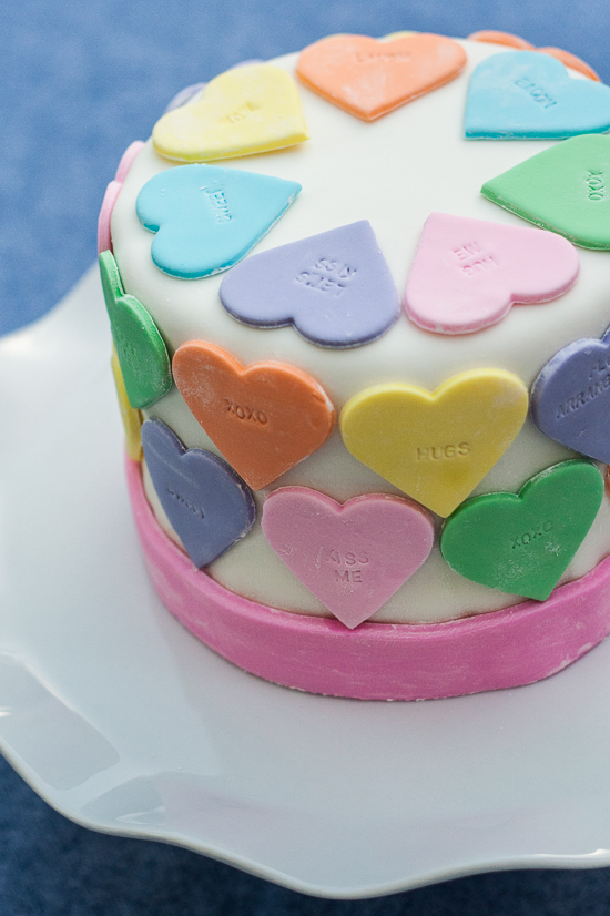 Pastel fondant hearts and a customizable letter stamp help create a personalized conversation hearts cake. It's the perfect cake for Valentine's Day!