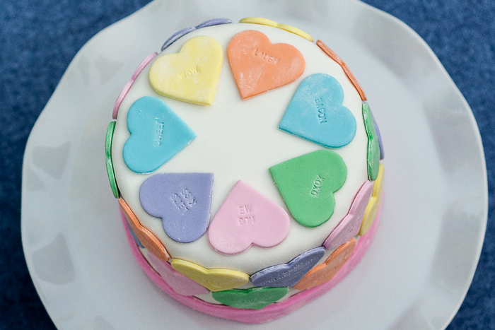 Pastel fondant hearts and a customizable letter stamp help create a personalized conversation hearts cake. It's the perfect cake for Valentine's Day!