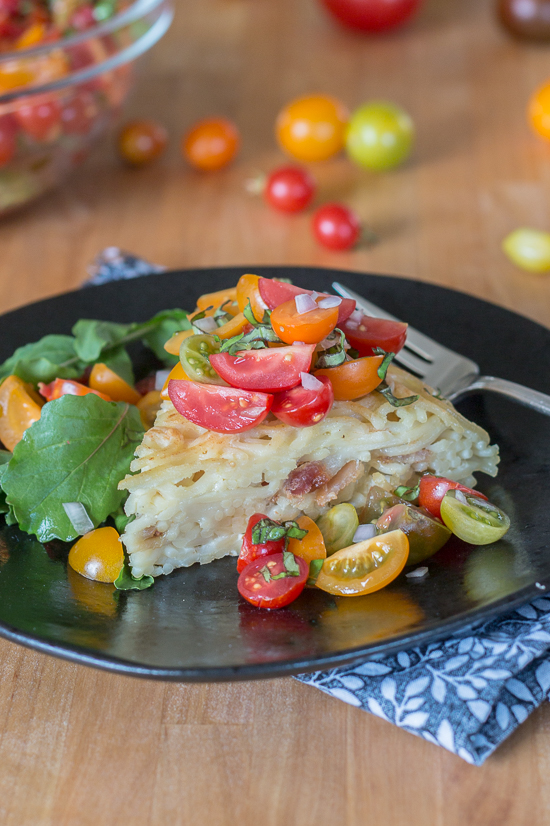 With bacon and cheese tucked in the center, this savory noodle cake tastes delicious topped with fresh summer tomatoes. This simple, flavorful recipe is easy to prepare. It's a great way to use up leftover spaghetti, too!