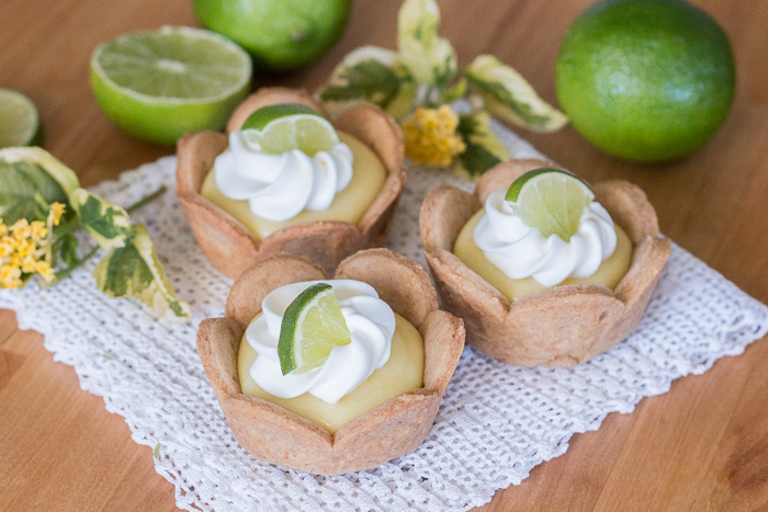 Homemade graham cracker cups filled with sweet, tangy lime curd come together in adorable little lime tarts. Simple to serve, these eat-by-hand treats make a perfect party dessert.