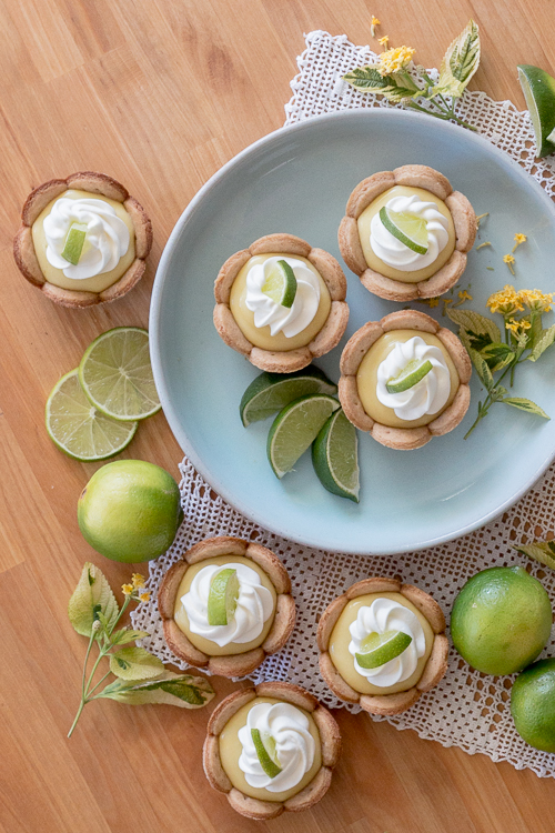 Homemade graham cracker cups filled with sweet, tangy lime curd come together in adorable little lime tarts. Simple to serve, these eat-by-hand treats make a perfect party dessert.