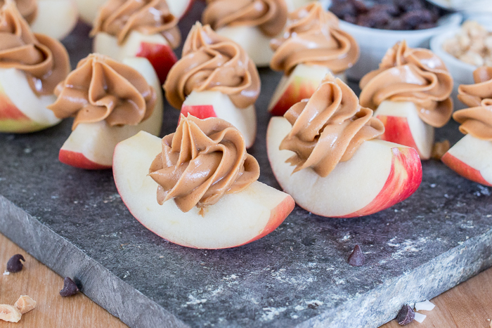 Dress up a simple, wholesome snack of Peanut Butter Apple Slices by piping creamy peanut butter in small spirals atop crisp, tart apples. Sprinkling toppings like mini chocolate chips, toasted coconut, or raisins over these apple-tizers adds to the fun of this easy, healthy snack. 