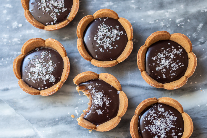 Spicy gingerbread cookie crusts provide a bold, flavorful backdrop for sweet caramel and rich, smooth ganache in these Mini Salted Caramel-Chocolate Tarts. 