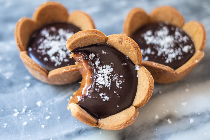 Spicy gingerbread cookie crusts provide a bold, flavorful backdrop for sweet caramel and rich, smooth ganache in these Mini Salted Caramel-Chocolate Tarts. 