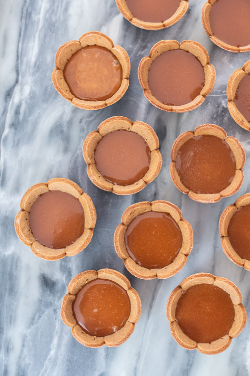 Spicy gingerbread cookie crusts provide a bold, flavorful backdrop for sweet caramel and rich, smooth ganache in these Mini Salted Caramel-Chocolate Tarts. 