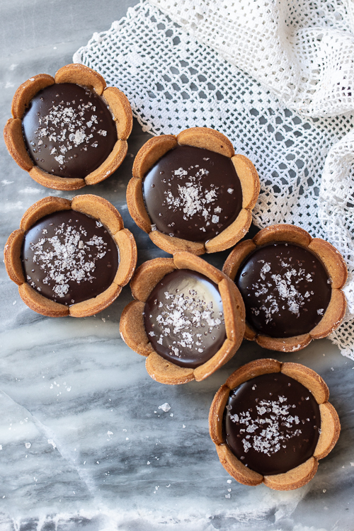 Spicy gingerbread cookie crusts provide a bold, flavorful backdrop for sweet caramel and rich, smooth ganache in these Mini Salted Caramel-Chocolate Tarts. 