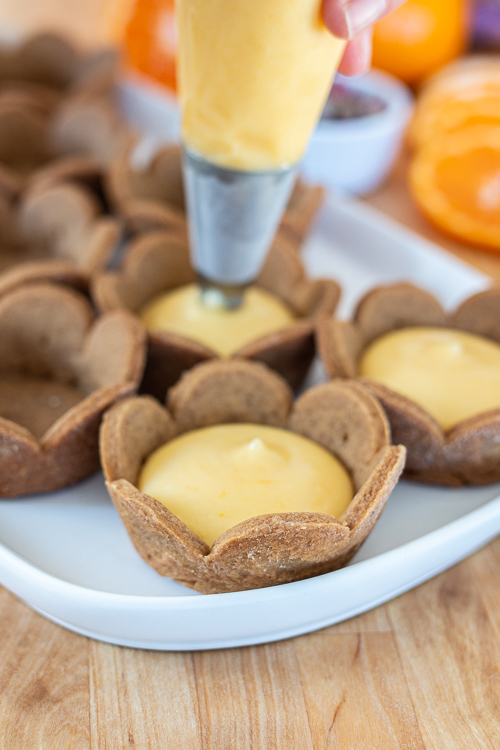 Mini Mandarin Tarts feature sweet, creamy mandarin curd layered into crisp gingerbread cookie cups.  The tangy citrus pairs so well with the gingerbread, delivering a bright, sunny flavor with a holiday twist.