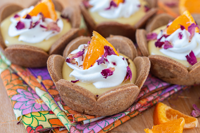 Mini Mandarin Tarts feature sweet, creamy mandarin curd layered into crisp gingerbread cookie cups.  The tangy citrus pairs so well with the gingerbread, delivering a bright, sunny flavor with a holiday twist.